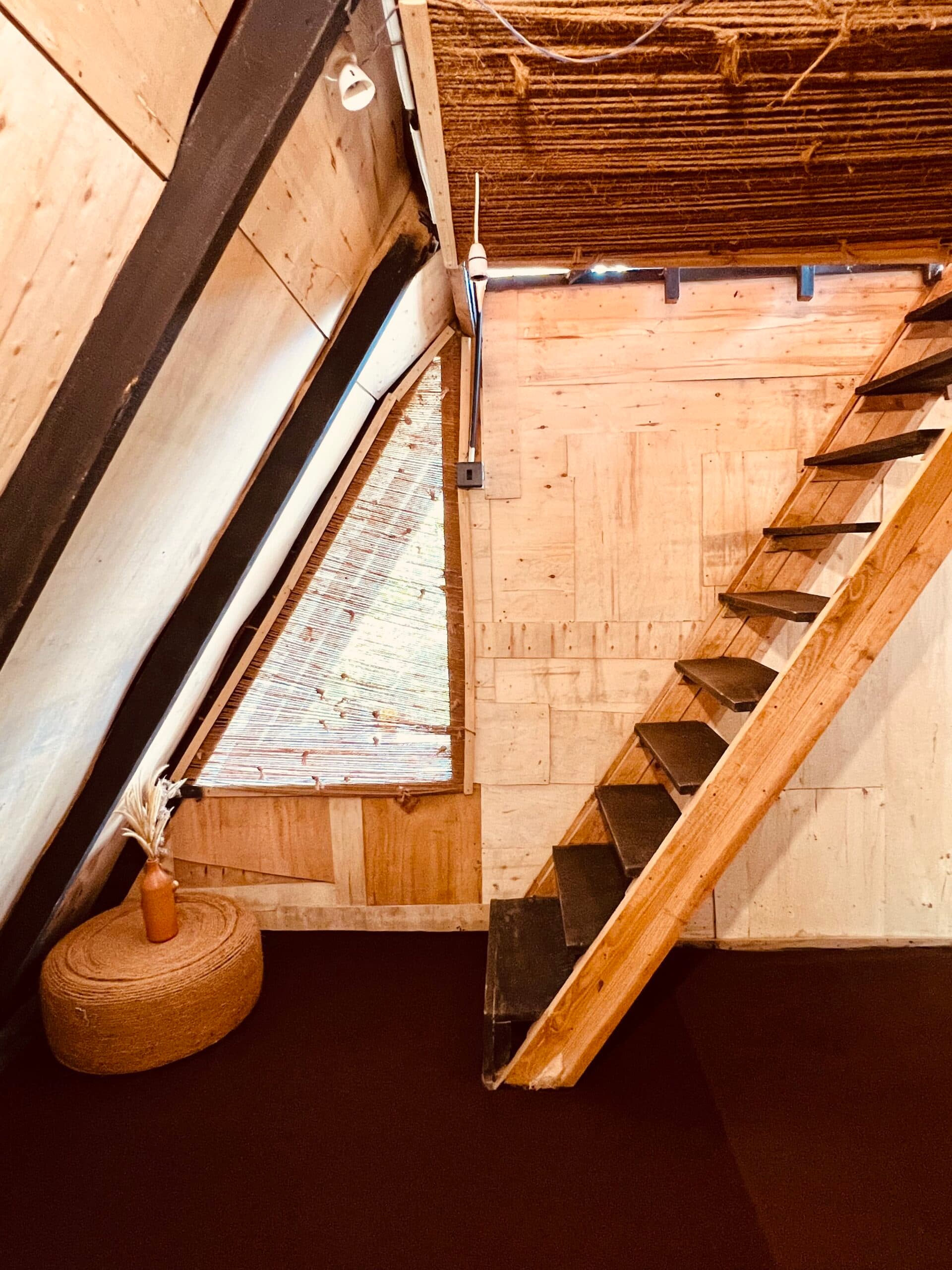The Vibe cabin — the ground floor, with a jute pouf and stairs up to the loft
